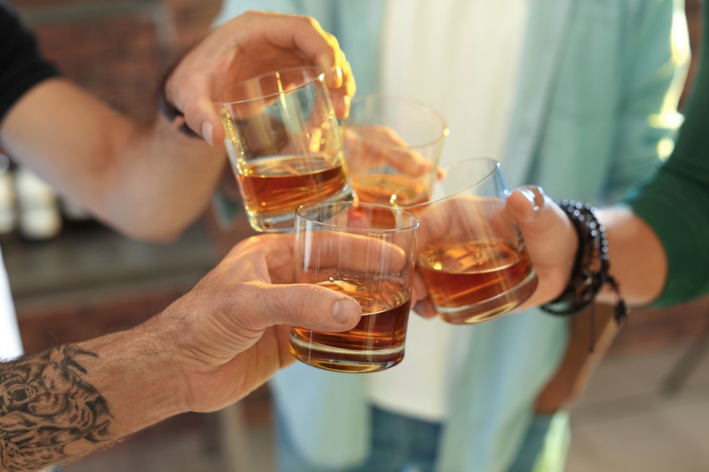 Close to friends toasting with glasses of whiskey indoors